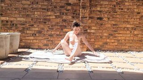 Inked dark haired doing stretches outdoors into the sun while being completely nude